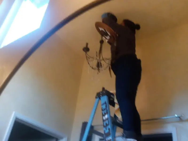Electrician installing a chandelier in a Nassau residence